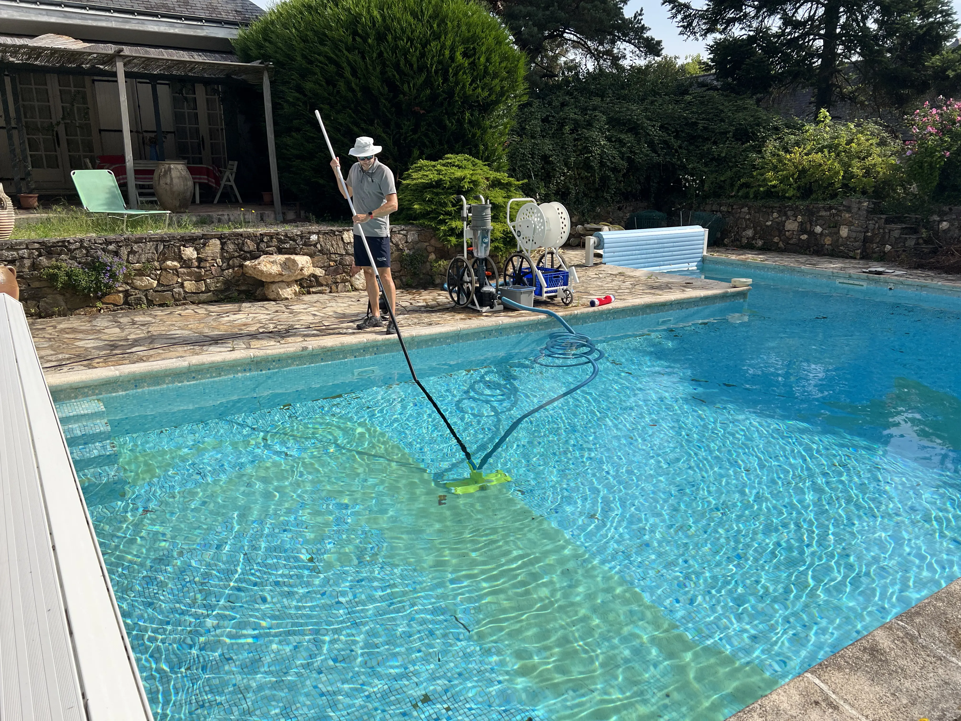 Technicien professionnel Quality Piscine en action, nettoyant une piscine résidentielle avec équipement spécialisé et perche de nettoyage à Angers